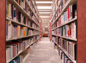 A photograph shows an aisle in a library. The aisle is the narrow walkway between two parallel bookshelves.