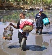 Residents carry their belongings through mud as they evacuate their homes in east Java.